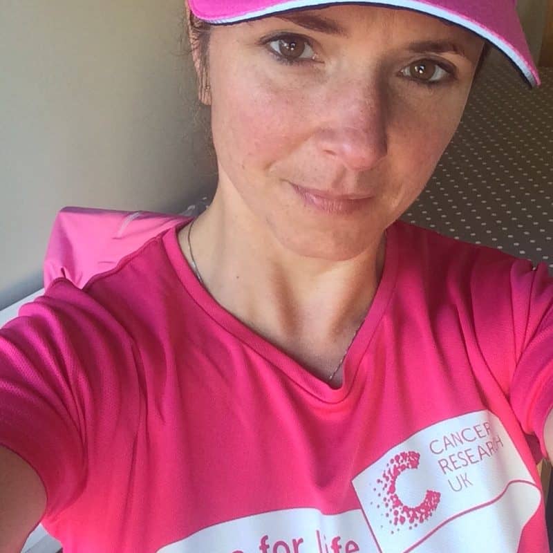 Woman in pink sportswear and cap participating in Race for Life charity event in the UK.