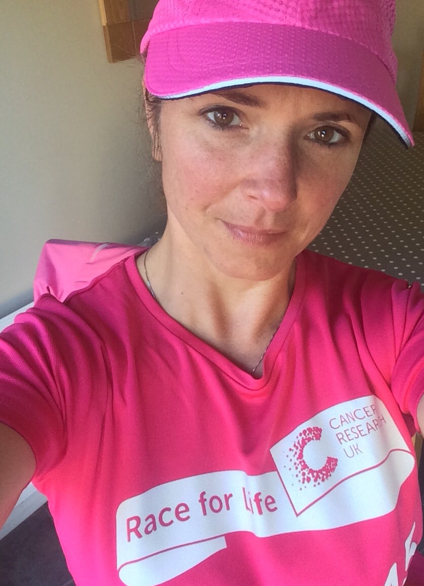Woman in pink sportswear and cap participating in Race for Life charity event in the UK.