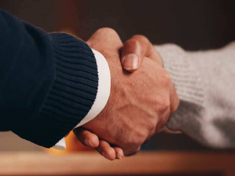 Close-up of two people shaking hands, symbolising partnership and agreement.